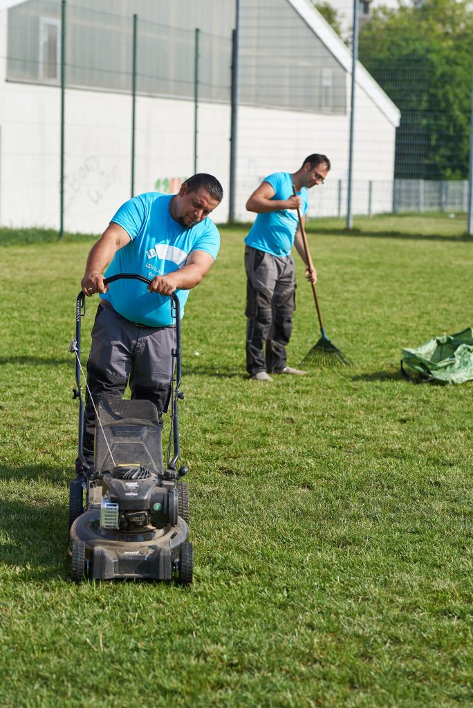 Mitarbeiter von LD-Hausbetreuung beim Rasenmähen und Laubrechen
